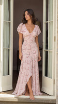 Woman wearing pink floral maxi dress standing in doorway
