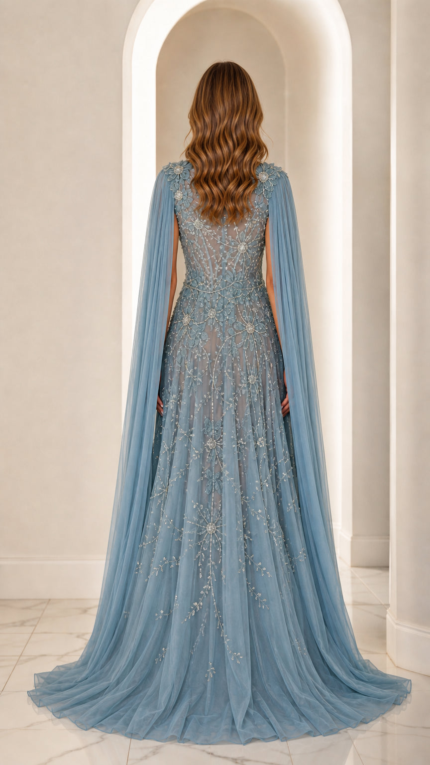 Back view of dusty blue embellished tulle evening gown showing flowing cape