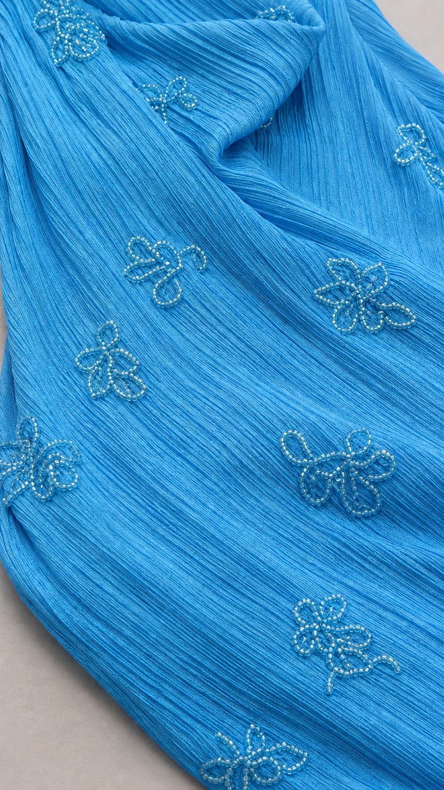 Close-up of fabric texture and beadwork on blue maxi dress
