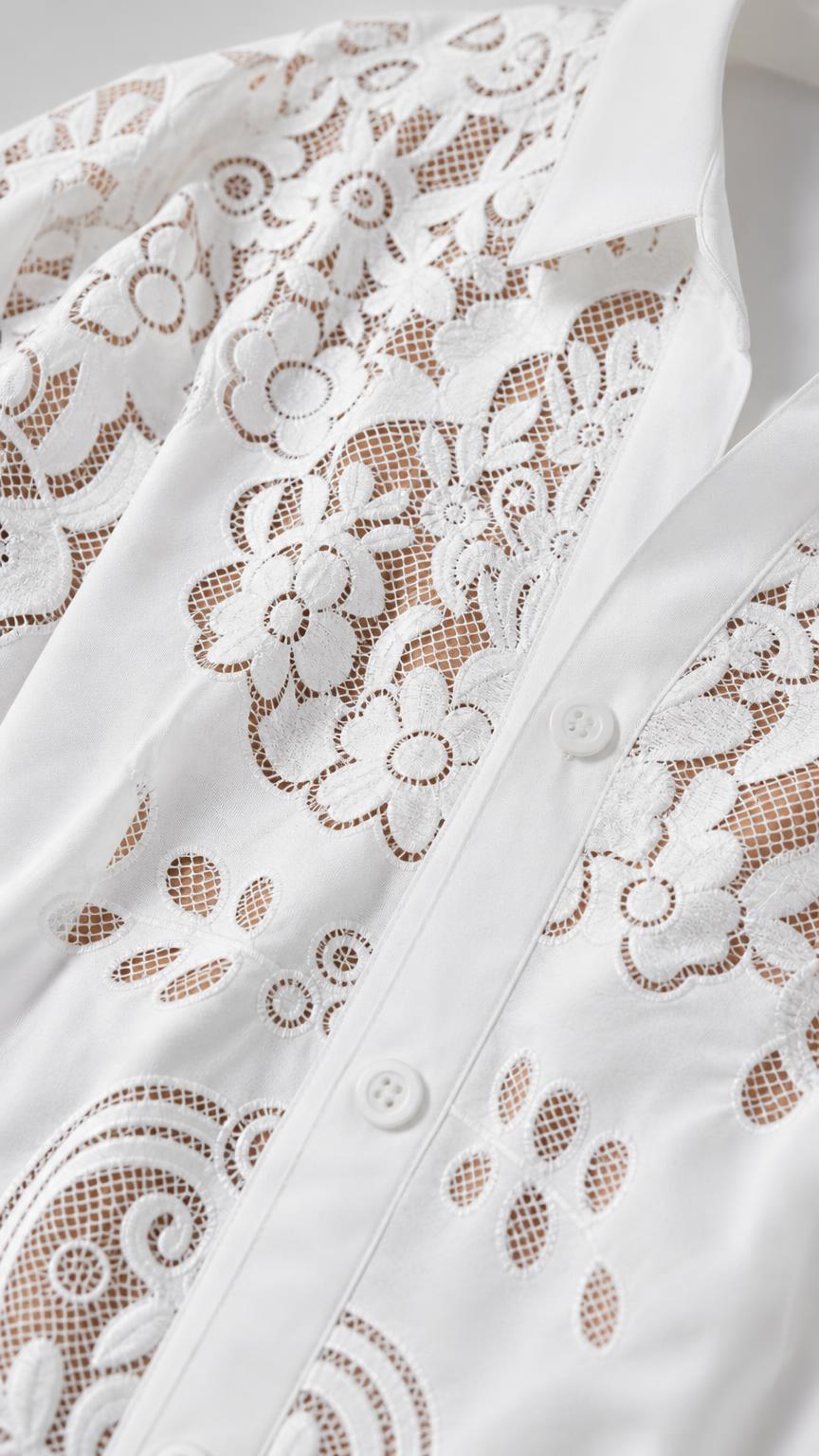 Closeup detail of the floral lace pattern and button closure on white shirt