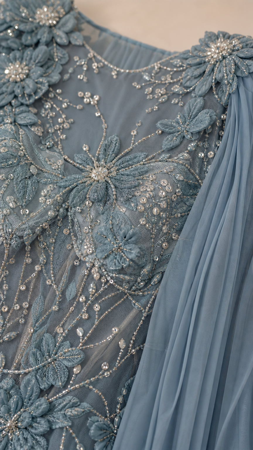 Close-up of intricate 3D floral beadwork and sheer illusion fabric on dusty blue gown